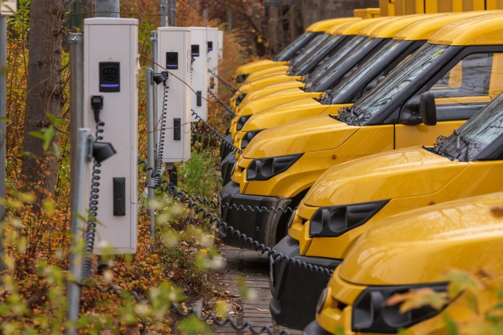 Yellow electric vehicles plugged into charging stations.